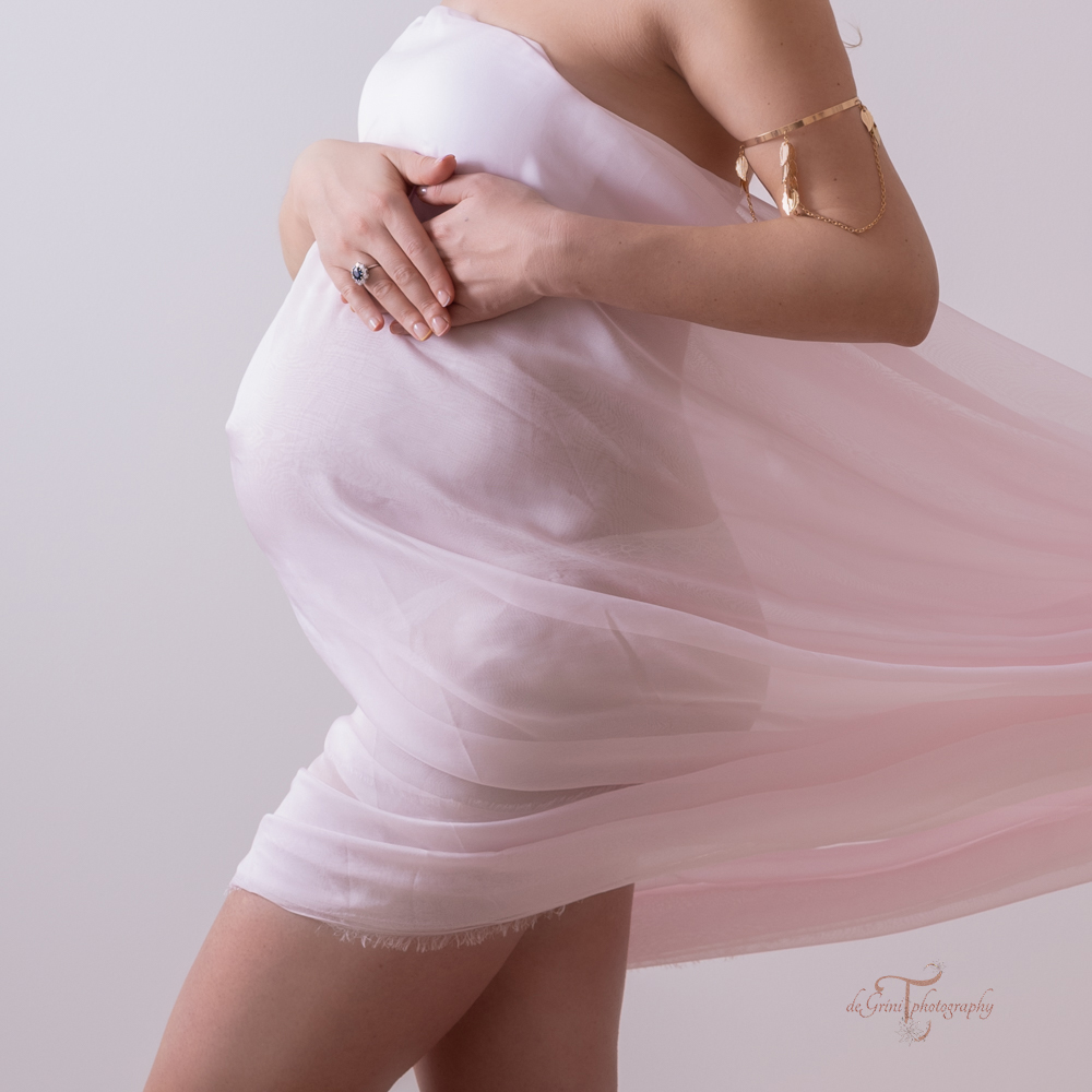 Studio maternity photo of a belly covered with pink chiffon fabric