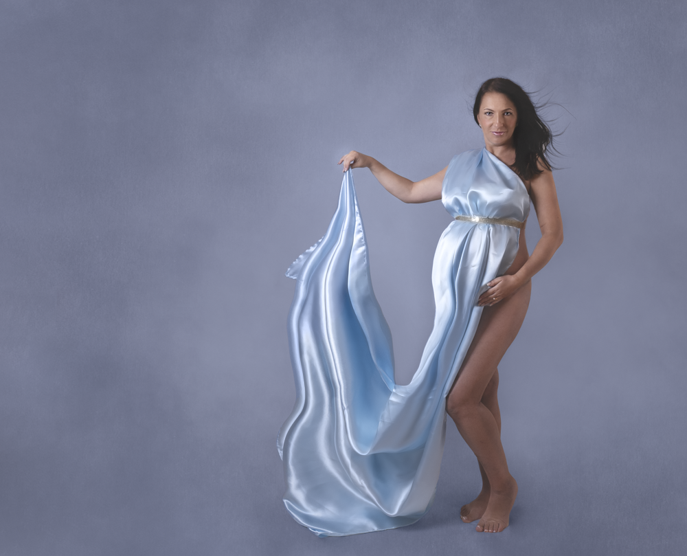 Studio maternity photo of a woman wearing a silky blue fabric