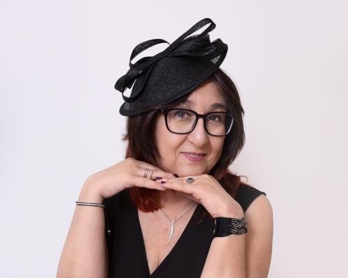 Studio headshot of a woman wearing black dress and fascinator